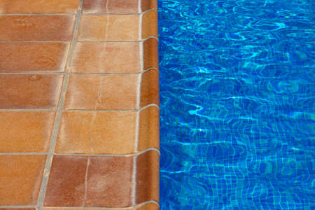 Orange tile floor at the edge of a pool with a blue background. Concepts like summer, vacation or refreshmentの写真素材