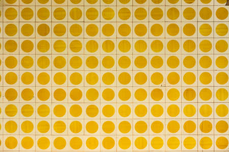 Facade of an old house with square tiles with yellow circles. Image for backgrounds or designsの写真素材