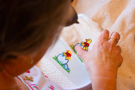 A woman creating a colorful cross stitch design for a child theme. Concepts of manual work or work at home.の写真素材