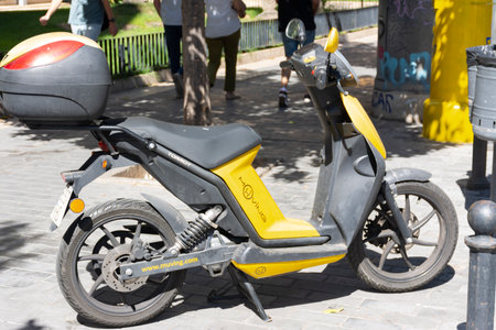 Valencia, Spain. September 27, 2020: Yellow rental smart electric motorcycle from Muving company parked on the sidewalk in a city, waiting for a customer to rent itのeditorial素材