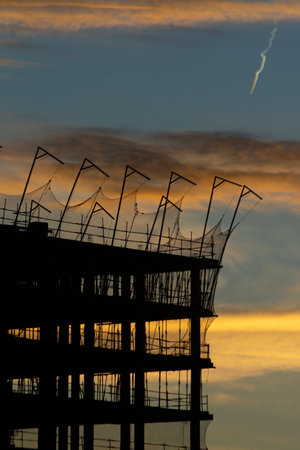 Silhouette of a building under construction with blue sky and yellow clouds at sunset or sunriseの写真素材