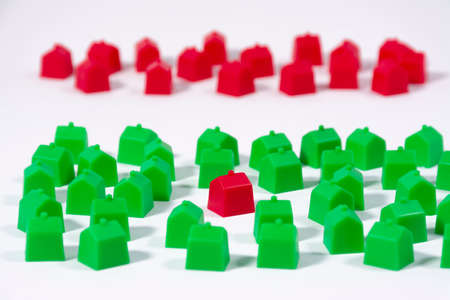 Groups of toy houses of two different colors on table and white background. Concepts such as choice, different neighborhoods or social classesの写真素材