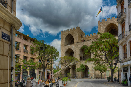 Valencia, Spain, April 17, 2021: Backside of Torres de Serranos, 33 meters high, the main gate of the medieval walled city, built by architect Pere Balaguer in the 14th century. Street bar terracesのeditorial素材