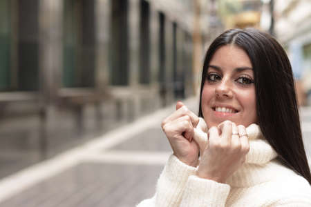 Young girl on the street in winter holding the collar of her sweater, feeling coldの写真素材