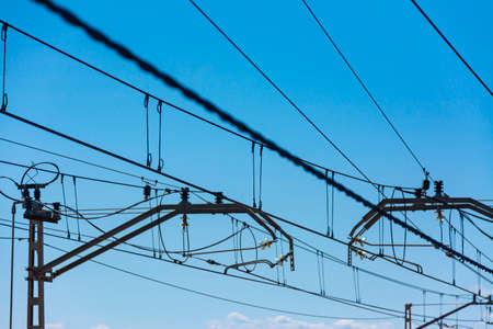 Group of tower and catenary cables of a train track with blue sky in the background, with selective focusの写真素材