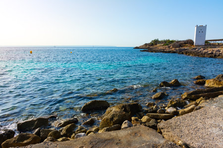 Tower on the rocky coast of Punta Des Bufador isthmus, in the background the other side of the bay of Palma, Majorca, Spainの写真素材