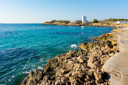 Ses Illetes, Mallorca, Spain. July 20, 2022 - View of the rocky coast of the isthmus of Punta Des Bufador. At background the Sa Torre island with the Ses Illetes towerのeditorial素材