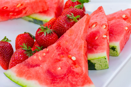 Watermelon slices along with several strawberries on a plate. Summer fruit, fresh and tastyの写真素材