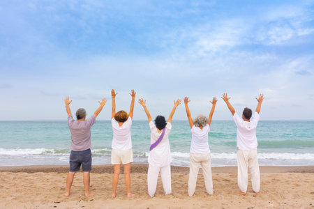 Group of women and men practicing kundalini yoga on the sand at the beach. Standing poseの写真素材