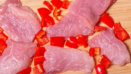 Fresh pork decorated with peppers on a wooden boardの写真素材