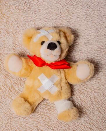 Sick teddy bear lies on a fur blanketの写真素材