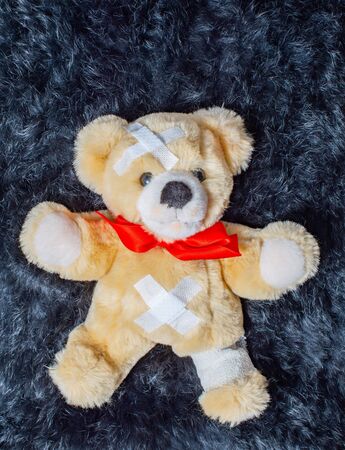 Sick teddy bear lies on a fur blanketの写真素材