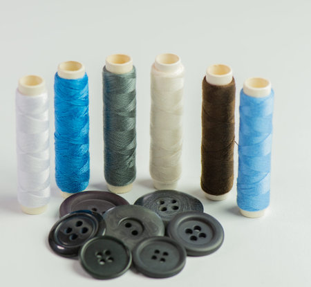 Sewing thread rolls in various colors at a tailor shop against a white background