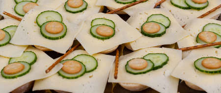 Bread rolls with slices of cheese served with sliced cucumberの写真素材