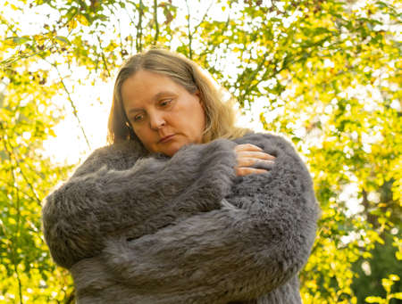 Woman in a rabbit fur jacket during a photo shoot in a city parkの写真素材