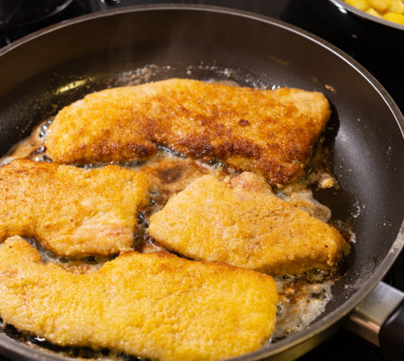 Pork schnitzel prepared on a stove top as a dish