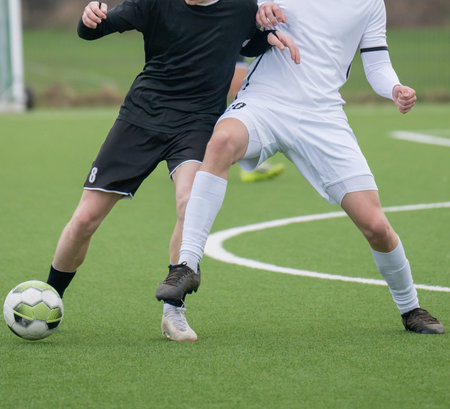 Football player on an artificial turf in a duel while playing footballの写真素材