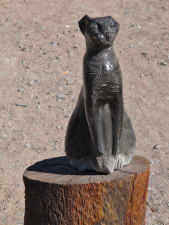 Egyptian cat statuette on a wooden logの写真素材
