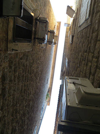 Wall air conditioners. Oblique skylight between medieval houses in a narrow street. Wall masonry...
