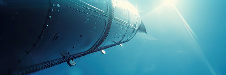 A striking close-up of a wind turbine reaches towards the sky, illuminated by the bright sun. The blades stretch high against a background of clear blue, showcasing a clean, renewable energy source in action. This moment captures the beauty and efficiency of wind power.の素材