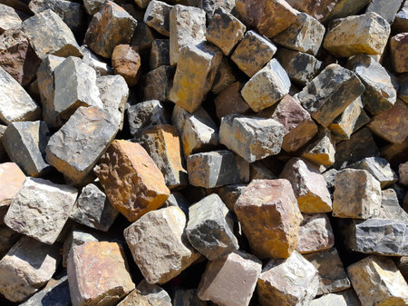 Various bricks with unique textures stacked together in a sunlit area, ready for use.の写真素材
