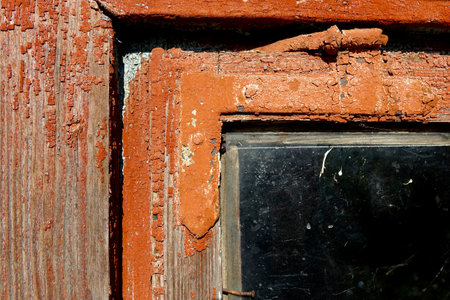 Weathered wooden window frame displays peeling paint and textured glass in a cozy interior.の写真素材