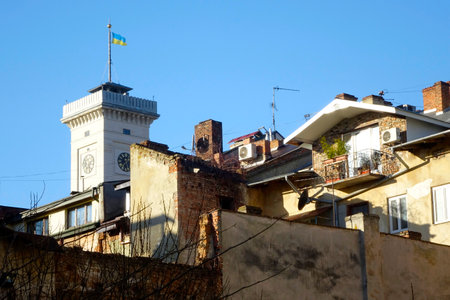 The flag of Ukraine flies proudly atop the town hall in Lviv, overlooking charming old buildings under a clear blue sky.の写真素材