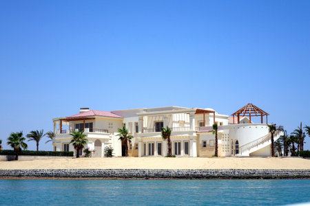 Villas designed in Nubian style stand against a clear blue sky by the Red Sea, surrounded by sandy beaches and palm trees in El Gouna, Egypt.のeditorial素材