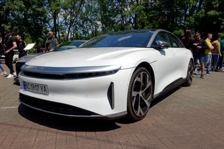 Lviv, Ukraine - June 1, 2023 A sleek white electric vehicle stands prominently in an outdoor venue, attracting curious onlookers who admire its modern design and innovative features duringのeditorial素材