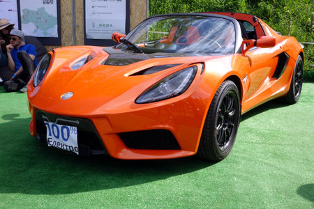 Lviv, Ukraine - June 6, 2017 A sleek bright orange sports car Detroit Electric SP01 showcases its design at an automotive event, surrounded by attendees and green grass under a clear skyのeditorial素材