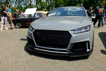 Lviv, Ukraine - June 1, 2023 A sleek, gray Audi TT RS sports car is prominently displayed at a lively automotive gathering in a park. Enthusiastic attendees admire various classicsのeditorial素材