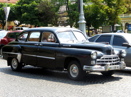 Lviv, Ukraine - June 22, 2013 A classic black GAZ-12 ZIM vintage car is parked along a busy city street. The sun shines down, highlighting the details of the car and the surrounding urban sceneryのeditorial素材