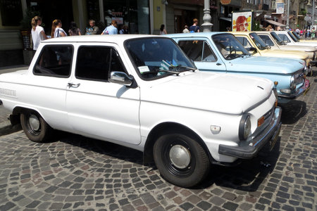 Lviv, Ukraine - June 22, 2013 Row of vintage cars ZAZ-968M Zaporozhets of various colors, including a white one, is parked on a cobblestone street. People walk by, enjoying the lively atmosphereのeditorial素材