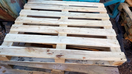 A wooden pallet is placed on top of other pallets at a construction site, surrounded by various...