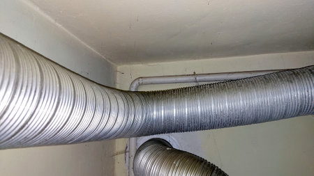 A new corrugated gas duct pipe connects to a domestic gas boiler in a utility room. The installation showcases flexible piping along the wall, ensuring efficient gas flow.の写真素材