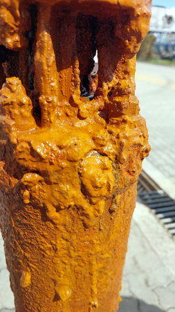 Striking rust formations cover an artesian pump, showing the impact of mineral-rich water in this outdoor setting under bright sunlight.の写真素材