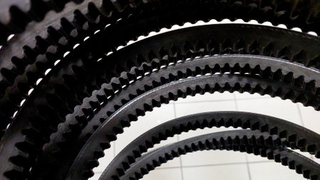 A collection of toothed V belts designed for drive systems is neatly arranged in a stack, showing their intricate grooves and robust design features.の写真素材