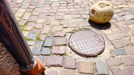 Strolling through the old town reveals beautifully laid cobblestones, featuring a round manhole cover and a unique stone. Time-worn paths tell stories of the past.の写真素材