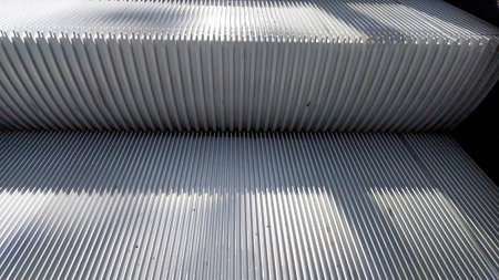 Escalator stairs extend into view with a smooth surface. Sunlight filters through, creating...