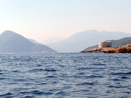 Visitors admire the impressive fort arza located on the lustica peninsula, overlooking the calm Adriatic sea and stunning mountainous landscape in montenegro during a sunny day.の写真素材