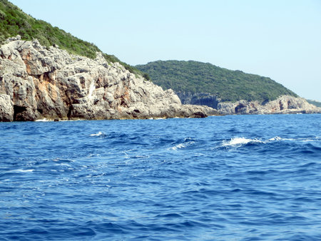 Bright blue waters stretch towards rugged cliffs in Montenegro, creating a tranquil atmosphere perfect for exploration and adventure beneath the sun.の写真素材
