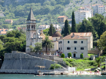 Viskovic Palace stands majestically by the beach, framed by lush greenery and charming houses along the coast of Perast, Montenegro.の写真素材