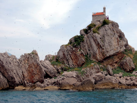 Visitors explore Sveta Nedjelja Island in Katic Nature Park, where a quaint church perches on rocky cliffs overlooking the sparkling Adriatic Sea.の写真素材