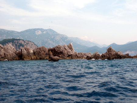 Katic Nature Park features rocky coastlines and clear waters surrounding Sveta Nedjelja Island. Scenic views highlight the islands natural beauty in Montenegro at sunset.の写真素材