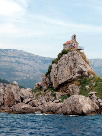 Nestled in Montenegro, Sveta Nedjelja Island features a charming church atop a rocky formation surrounded by tranquil waters and stunning landscapes at Katic Nature Park.の写真素材