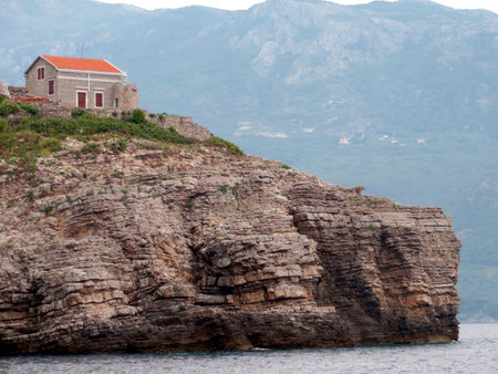 View of the small lighthouse on Sveti Nikola island in Montenegro. Nestled on rocky cliffs, it offers a picturesque sight against the Adriatic Sea backdrop.の写真素材