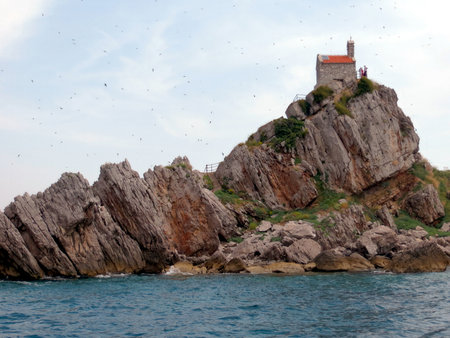 Sveta Nedjelja Island features a beautiful church atop rocky terrain surrounded by clear waters in Katic Nature Park. This serene setting invites exploration and relaxation.の写真素材