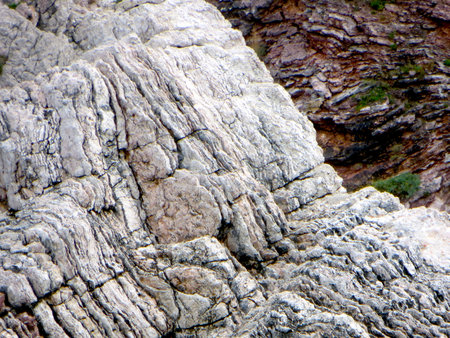 Jagged rocks dominate the coastal landscape of Montenegro, where the Adriatic Sea meets rugged cliffs under a clear sky. Nature reveals its raw form along the shoreline.の写真素材