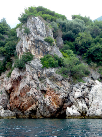 Gorgeous rocky coast of Montenegro features steep cliffs adorned with vibrant greenery next to the crystal-clear Adriatic Sea, creating a peaceful atmosphere.の写真素材