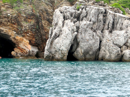 Visitors enjoy the striking rocky formations of Sveti Nikola island, surrounded by the crystal-clear waters of the Adriatic Sea on a sunny day.の写真素材